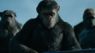 Gun-holding Caesar surrounded by other apes in War for the Planet of the Apes