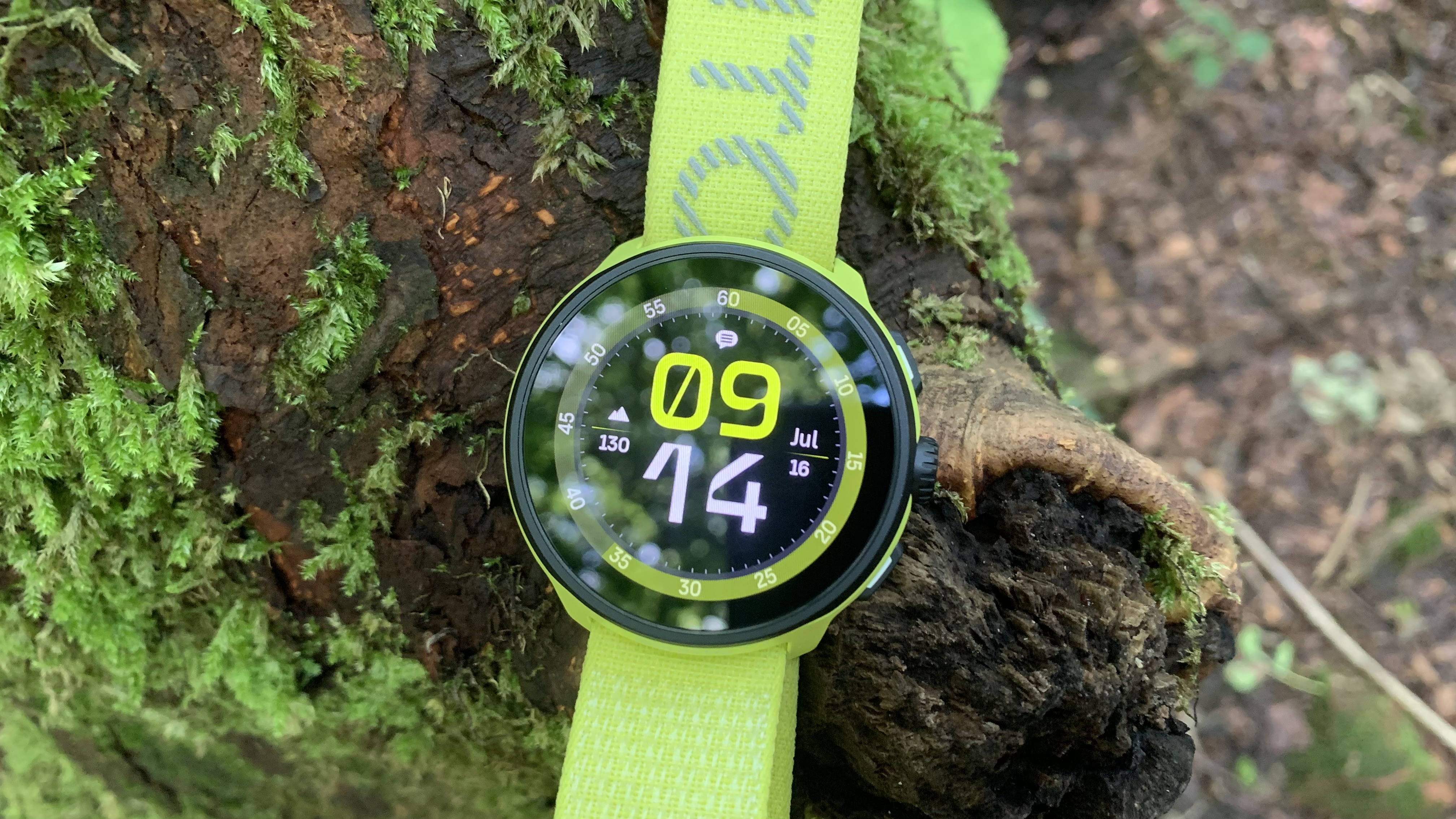 A yellow Suunto Run watch on a tree stump