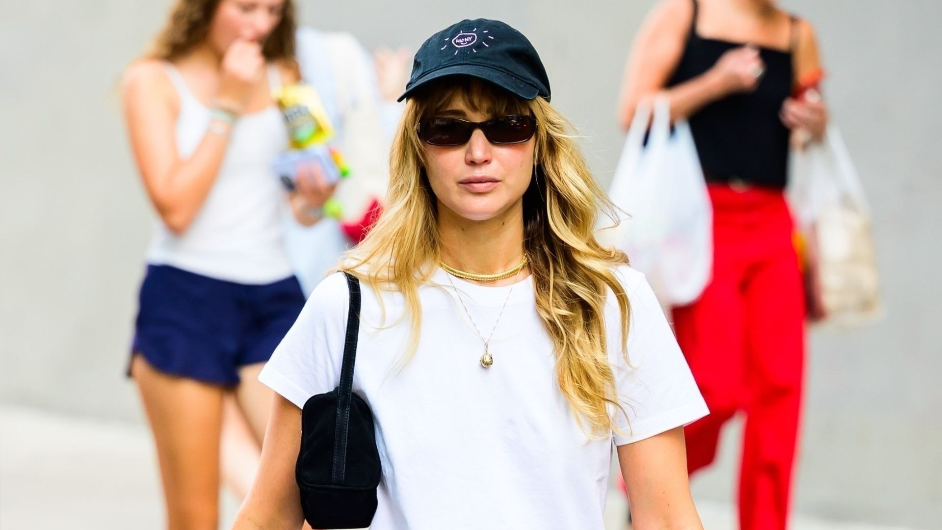 Jennifer Lawrence wears baggy jeans with sandals and a leather belt.