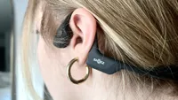 The Shokz OpenRun Pro bone conduction headphones worn over a woman's ear