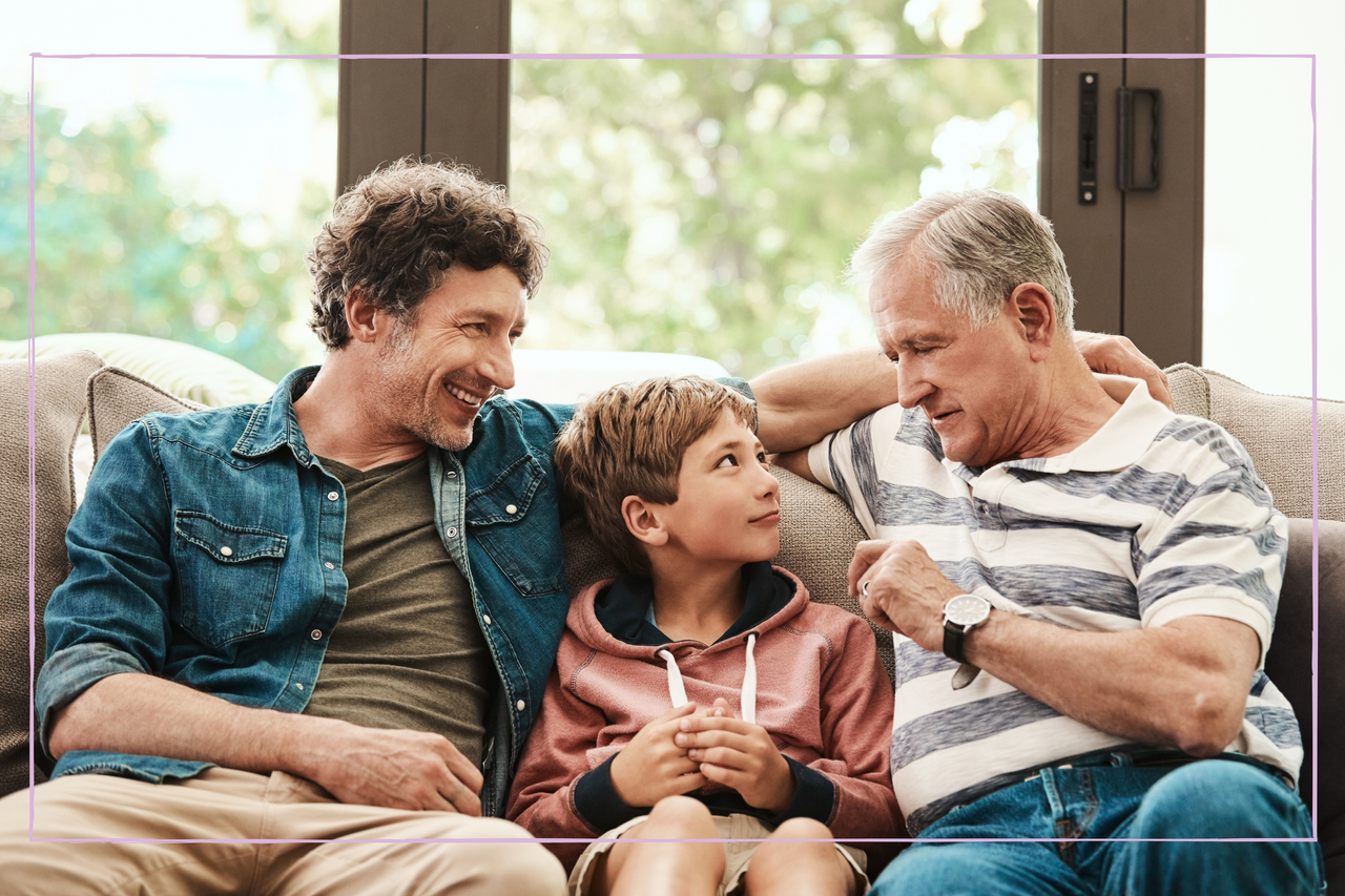 boy sat with father and grandfather either side of him on sofa