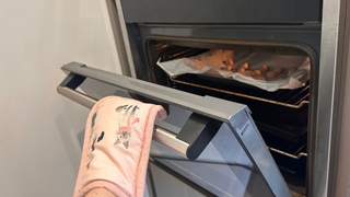 Megan putting the homemade cat treats into the oven using a cat print oven glove