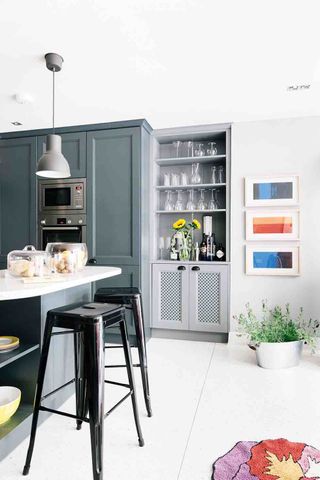 fitted bar dresser in a modern kitchen in an Edwardian home, white floor, artwork, black metal bar stools, kitchen island