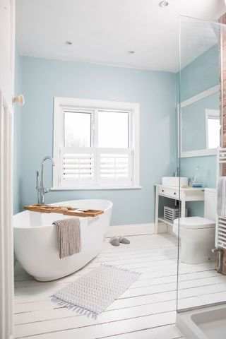 bathroom renovation with painted floorboards and freestanding bath