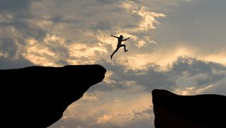 Person jumping through gap between two cliffs