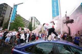 An England climbs onto the roof of a car