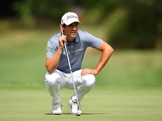 Matteo Manassero reading a putt on the putting green in a crouched position