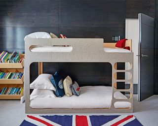A kids bedroom with a simple loft bed and union jack rug