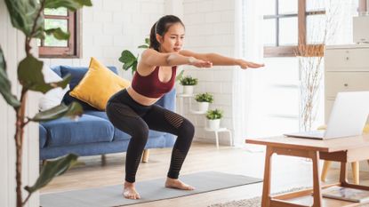 Woman performing a bodyweight squat in her living room