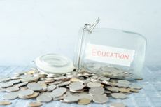 Coins and glass money jar with education label, financial concept.