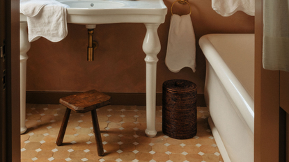 a woven brown bathroom bin in a tiled, classic bathroom