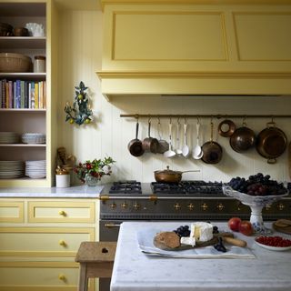 yellow kitchen with french range cooker and brass utensil rail
