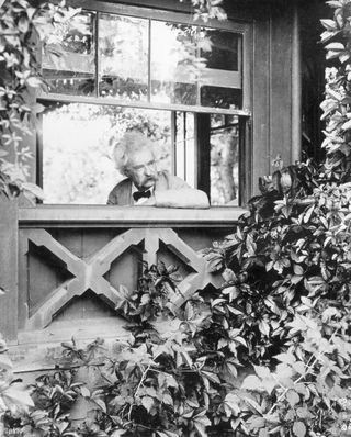 Mark Twain at his writer's desk in Elmira, NY, looking out of the window.