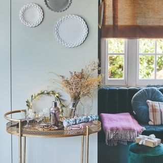 A bar cart decorated for Christmas with a window seating next to it