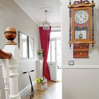 white hallway with wall clock and flower vase