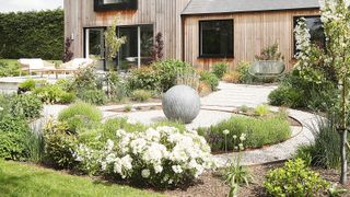 A beautifully landscaped garden with circular patio and sculpture