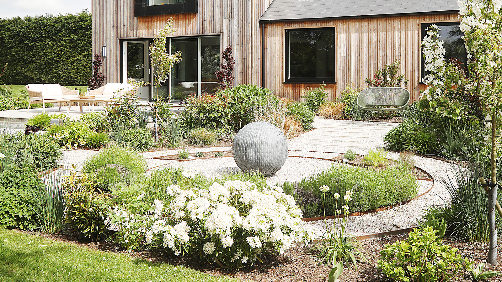 A beautifully landscaped garden with circular patio and sculpture