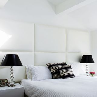 bedroom with white wall white bed with cushions and bedside lamps