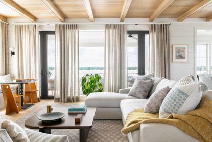 Grey curtains and rug, cream sofa with yellow blanket, designed by Cortney Bishop