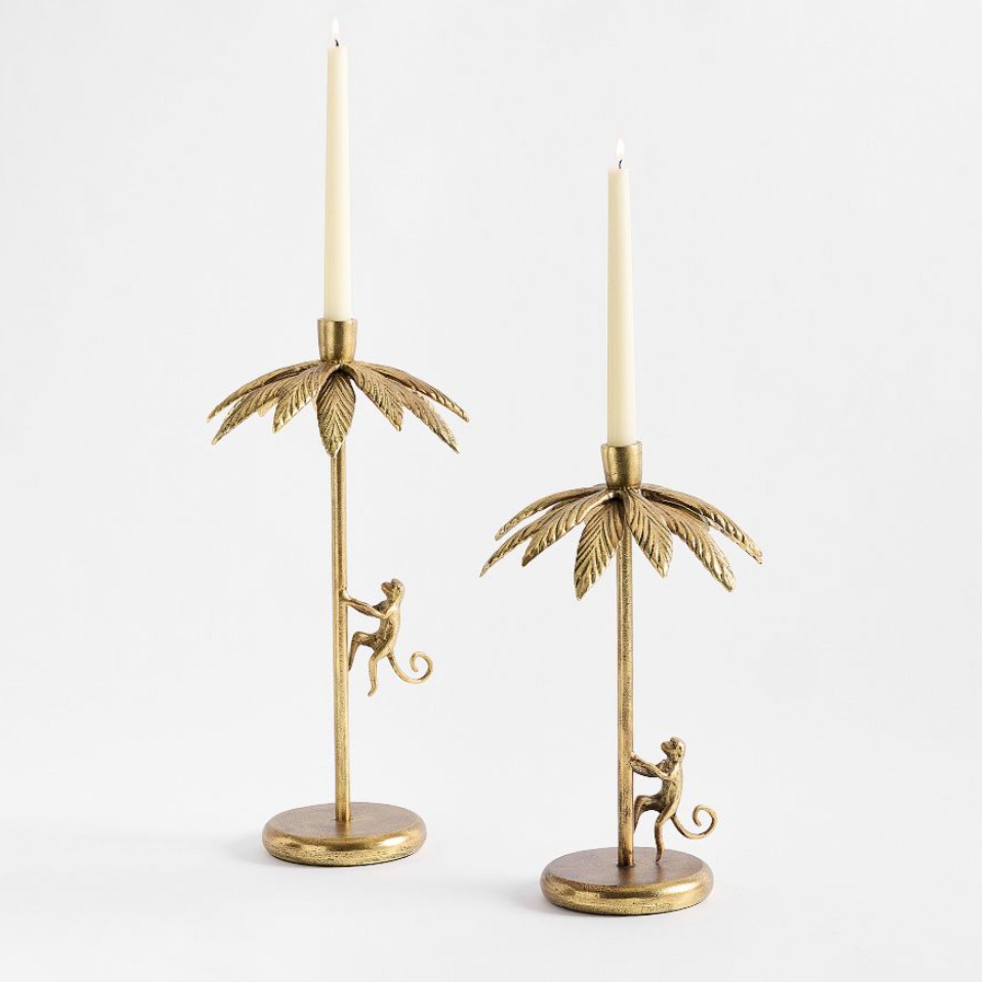 Pair of gold colored candlesticks with monkeys and palm leaves