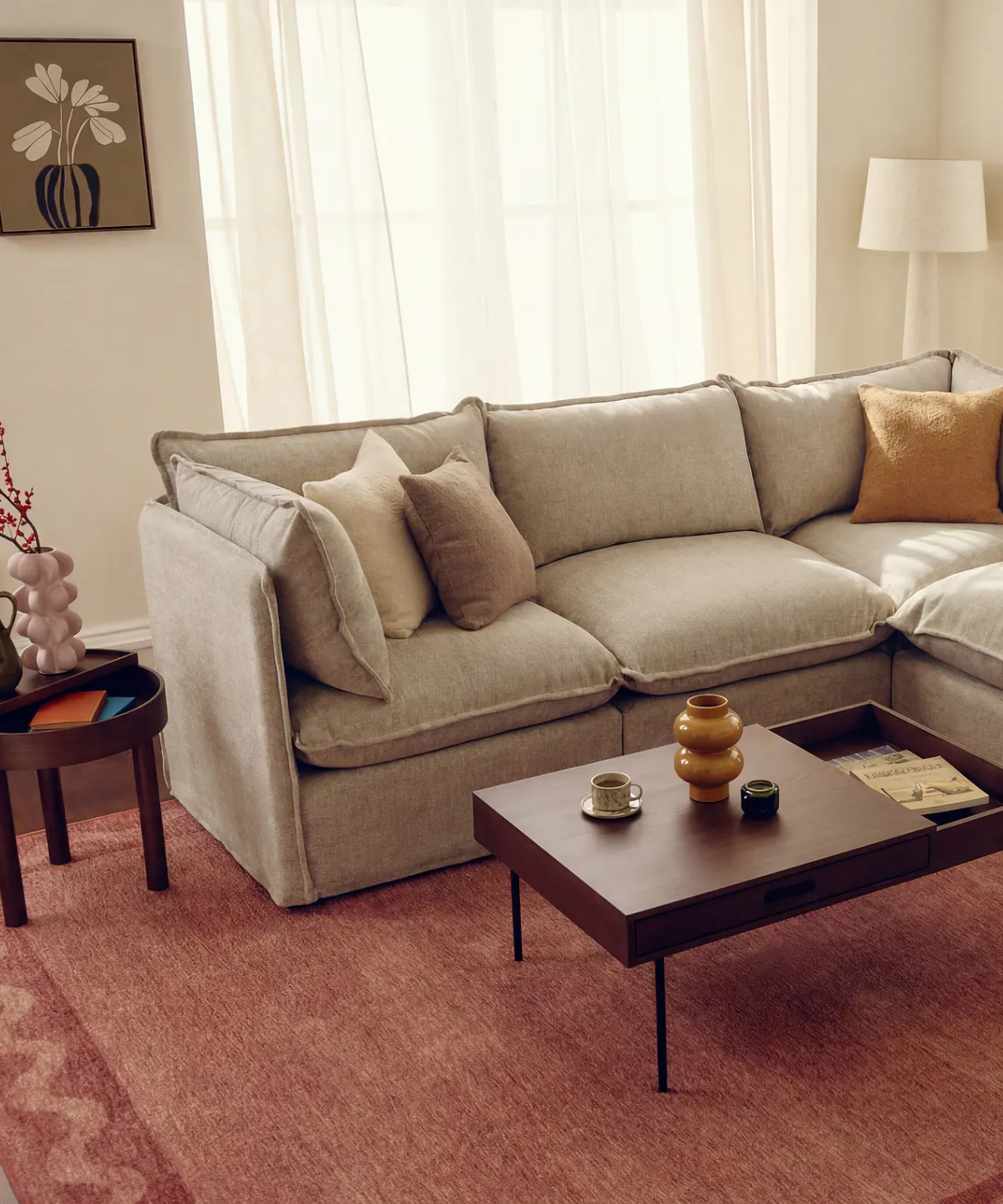 a tan sofa in a room with a red rug and dark wood accent furniture