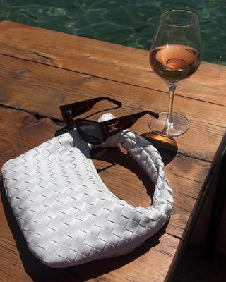 Table with wine glass, sunglasses, white bag