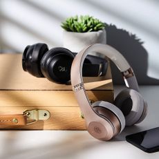 white and black wireless headphones wooden box and plant in white pot