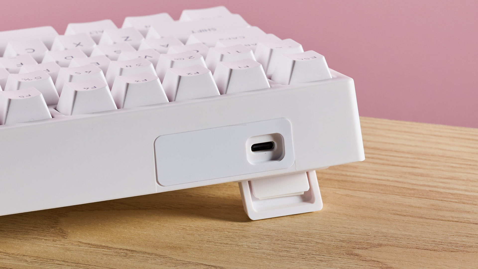 Close-up of USB-C port and feet on Gamakay TK75HE V2 on desk with pink wall in background