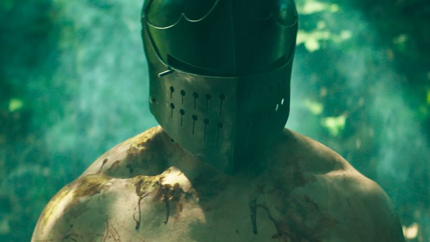 A shirtless, bloody man wearing a knight's helmet