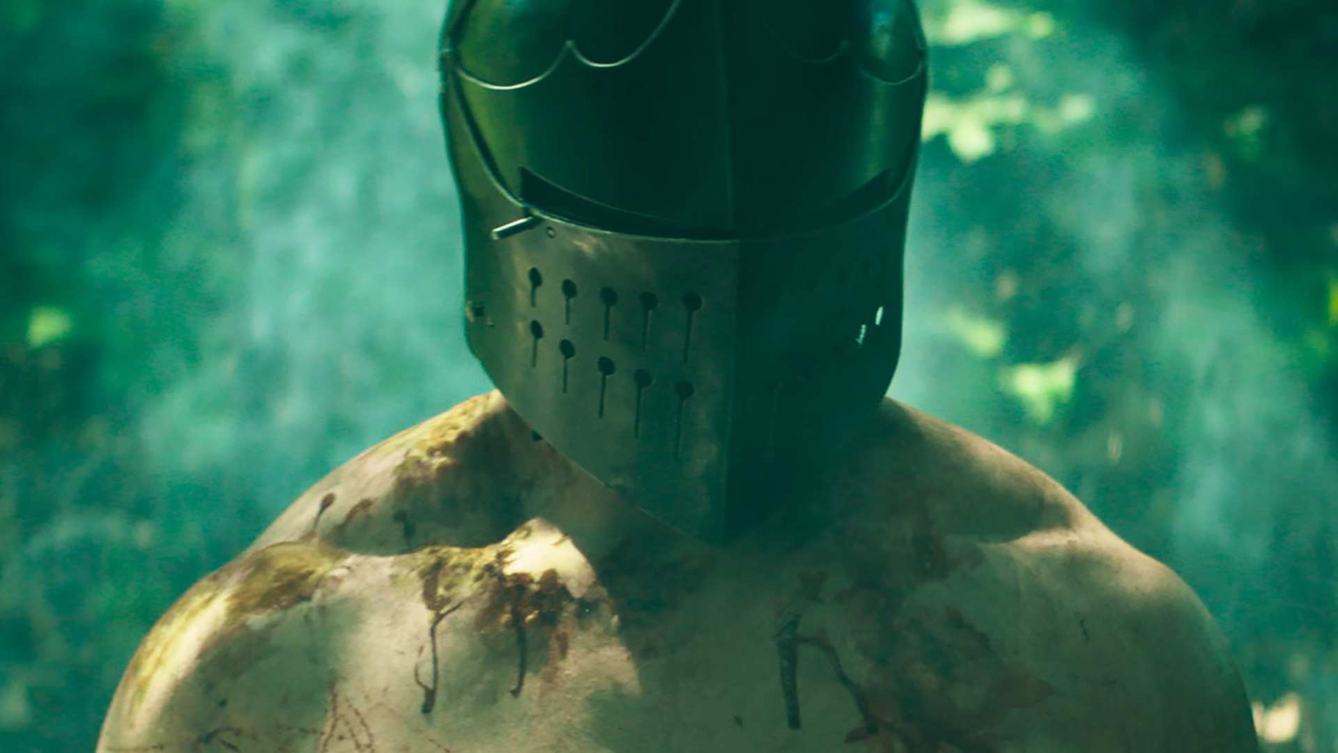A shirtless, bloody man wearing a knight's helmet