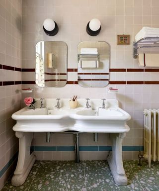 vintage style bathroom with a double sink vanity and mirrors with green terrazzo floor