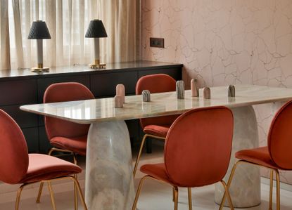 A dining room with pink wall tiles and white marble table