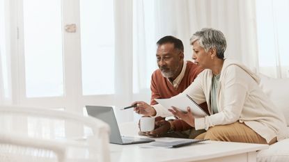 Mature couple at home with laptop and documents for financial planning