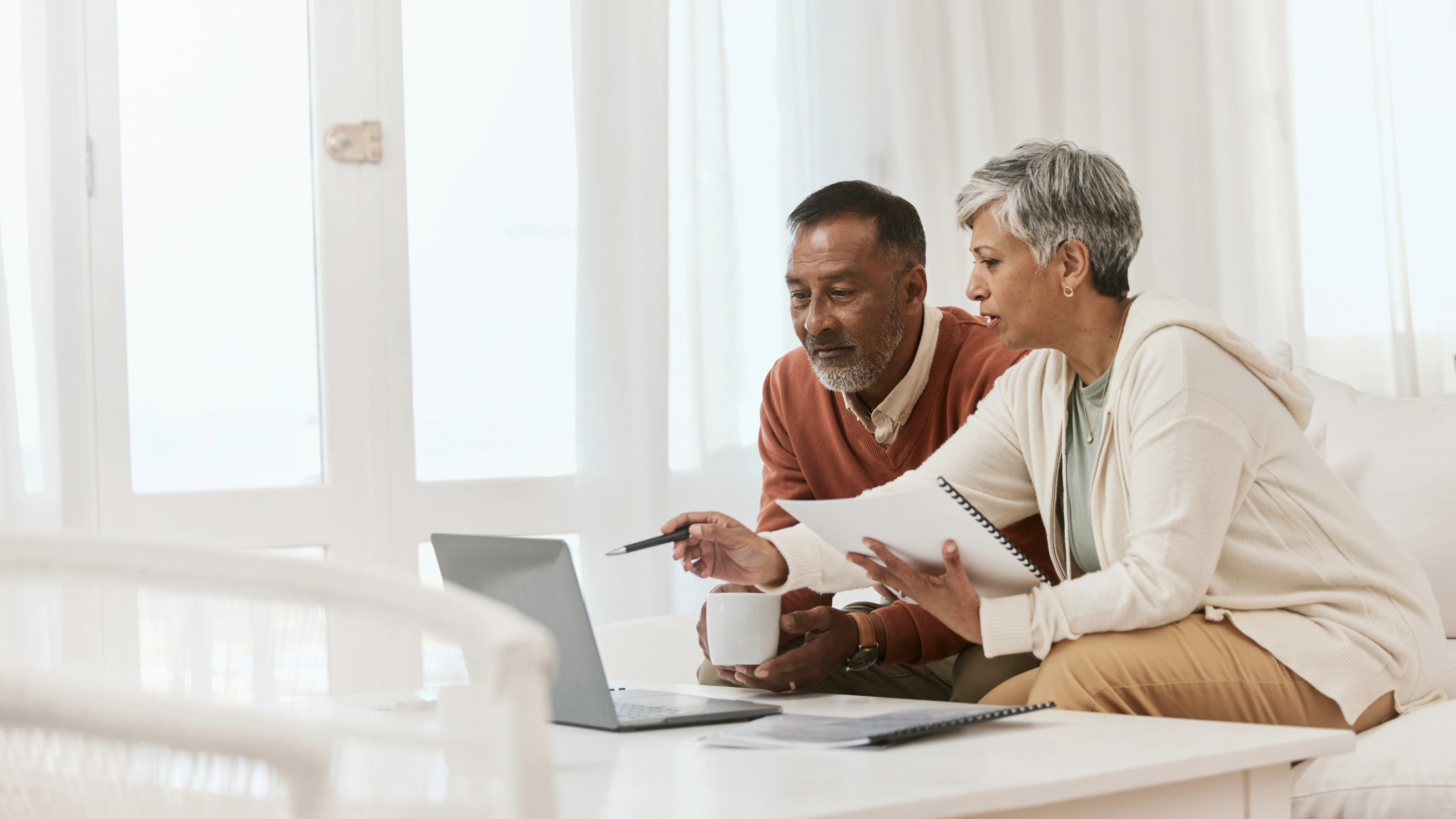Mature couple at home with laptop and documents for financial planning