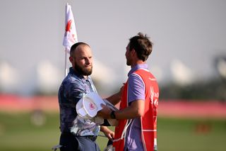 Tyrrell Hatton shakes hands with his caddie on the 18th green