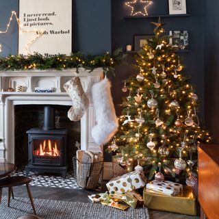 navy blue living room with Christmas tree and fireplace and Christmas stockings hanging on the mantel