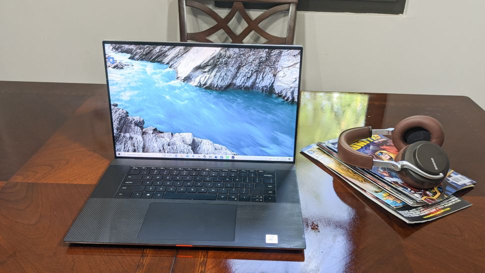Dell XPS 17 on a dining table with a pair of headphones and a collection of magazines