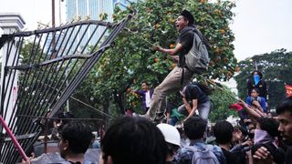 A protester tears down a fence in Indonesia