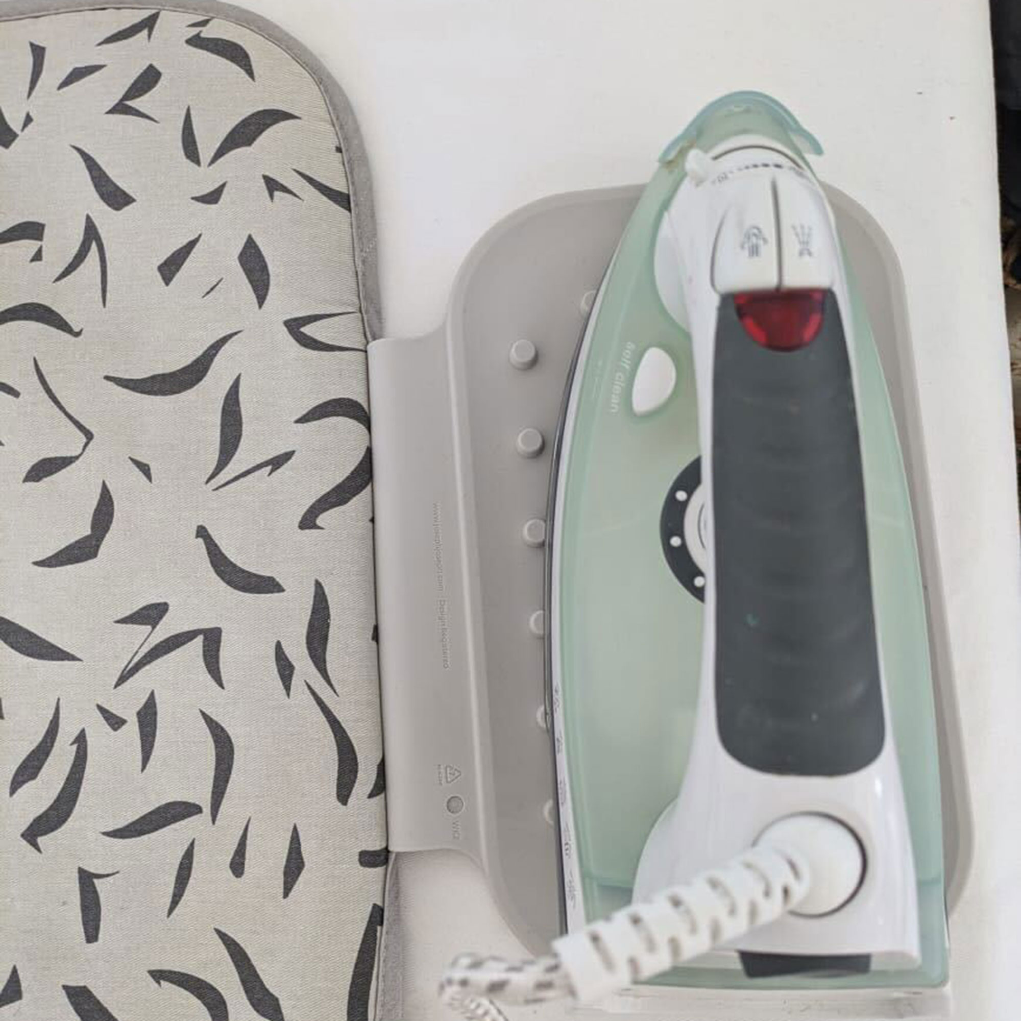 Grey patterned ironing mat on table with iron resting on silicone section