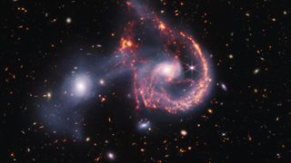 James webb telescope image of a galaxy merger, with spirals in glowing red light