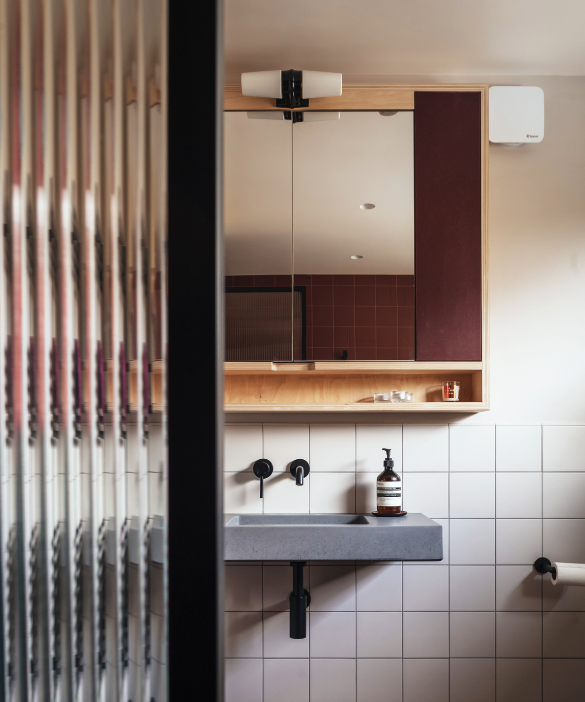 Bathroom sink and mirror behind the view of a glass partition