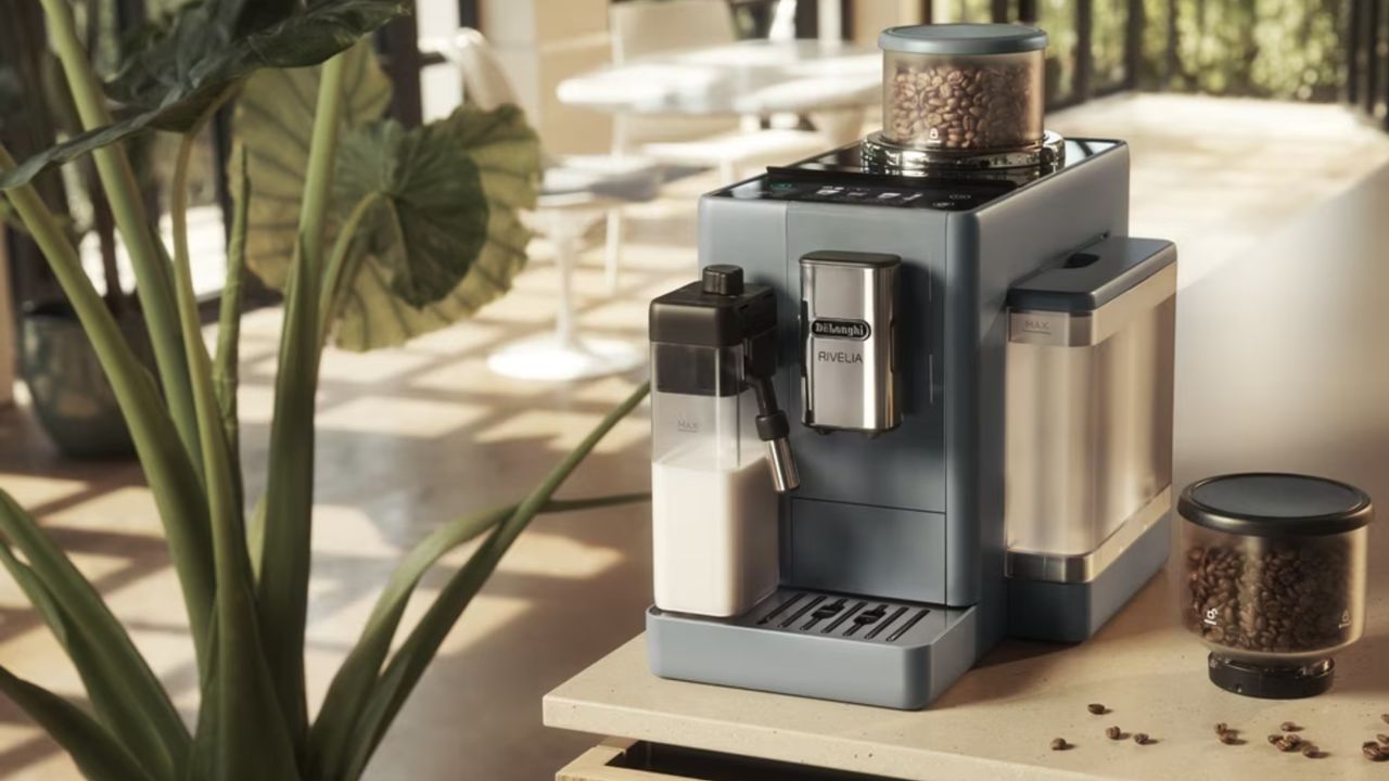 De&#039;Longhi Rivelia fully automatic bean-to-cup coffee maker in pebble grey on light wood countertop with additional hopper