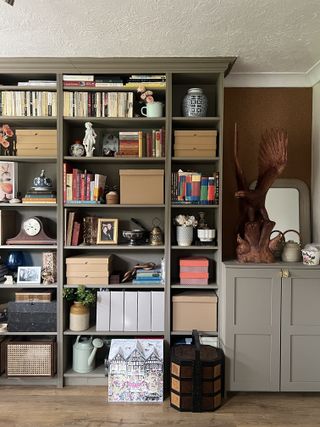 A living room with wooden floors and built-in shelving painted in a beige color