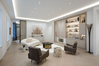 A white living room with cove lighting and recessed lighting within the bookcases