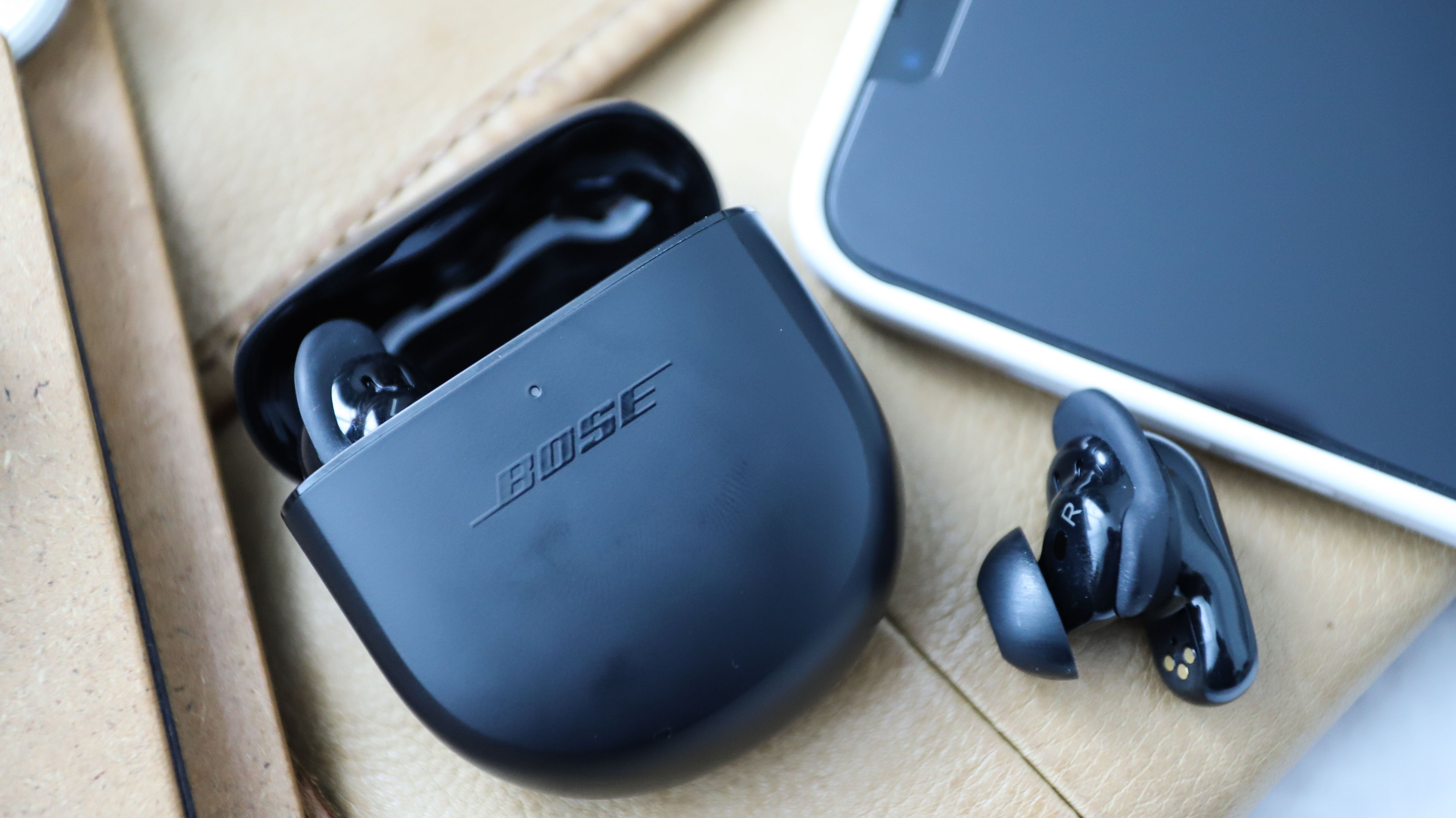 En Bose QuietComfort Earbuds 2 utanför fodralet med en inuti.