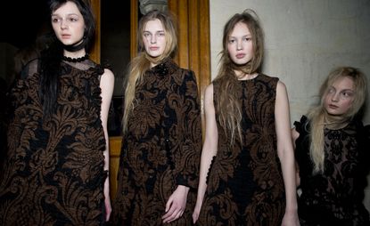 four female models wearing brown dresses with a tapestry design 