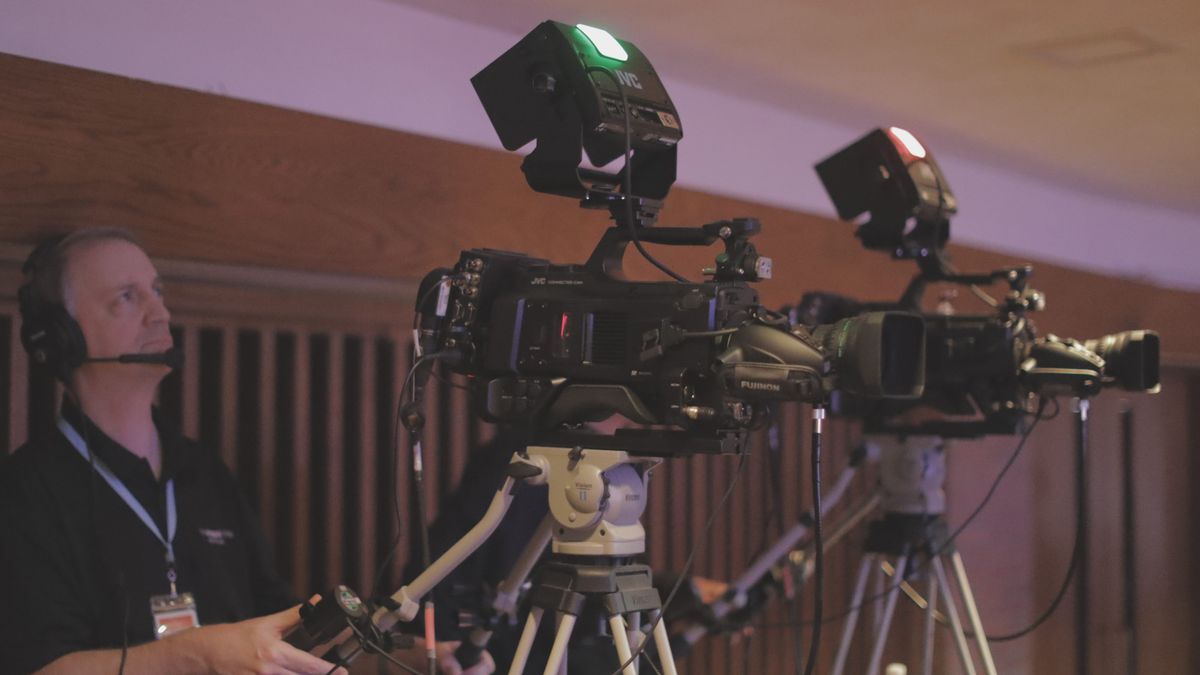 A cameraman films a house of worship service with two JVC Professional cameras. 