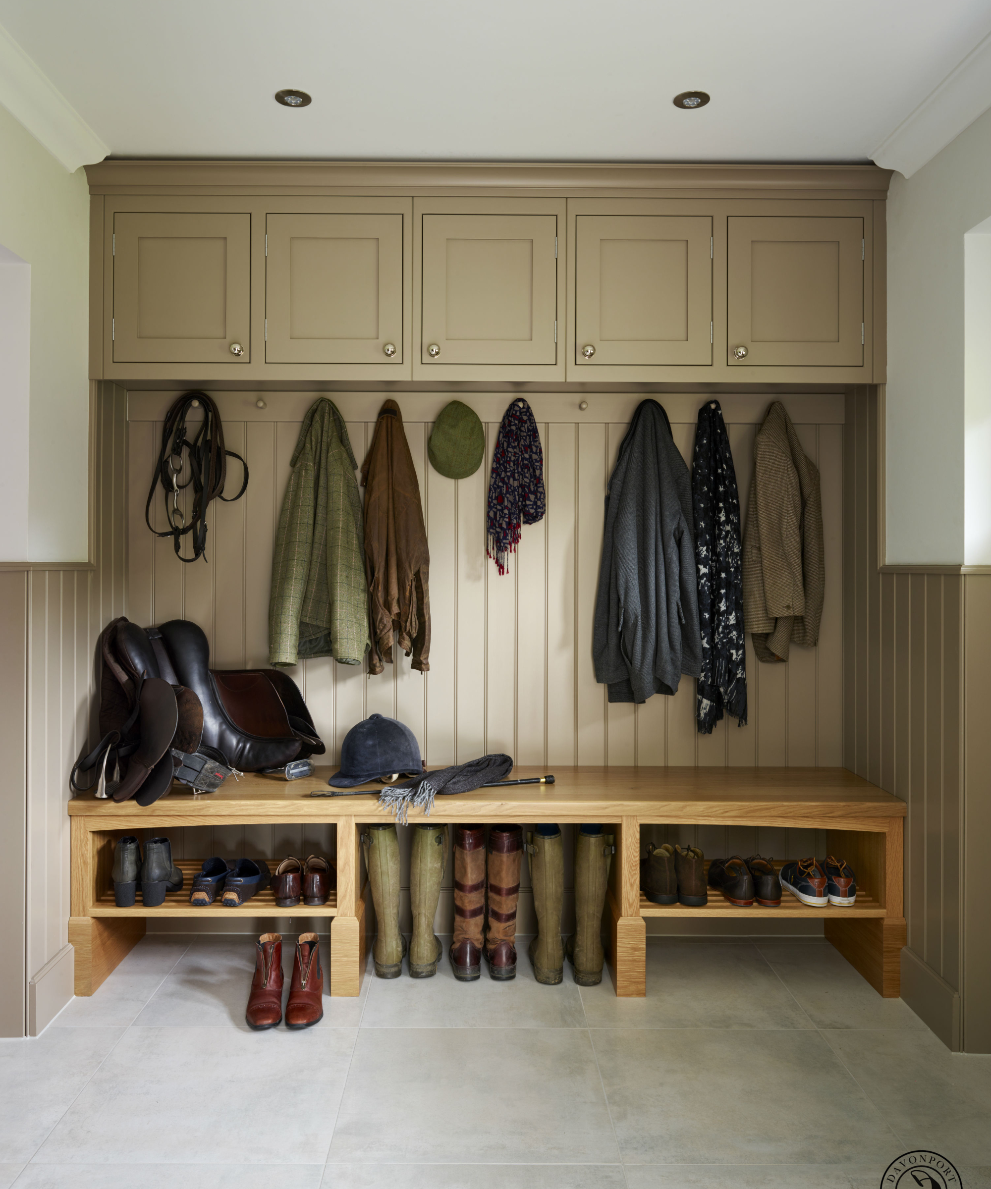 boot room with seating area and shelving below, high level fitted cupboards above and panelled section with hooks