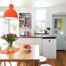 neutral kitchen with wooden table, orange ceiling light and dishwasher