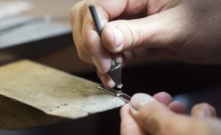 A Lindberg goldsmith sets a princess cut diamond on a gold frame